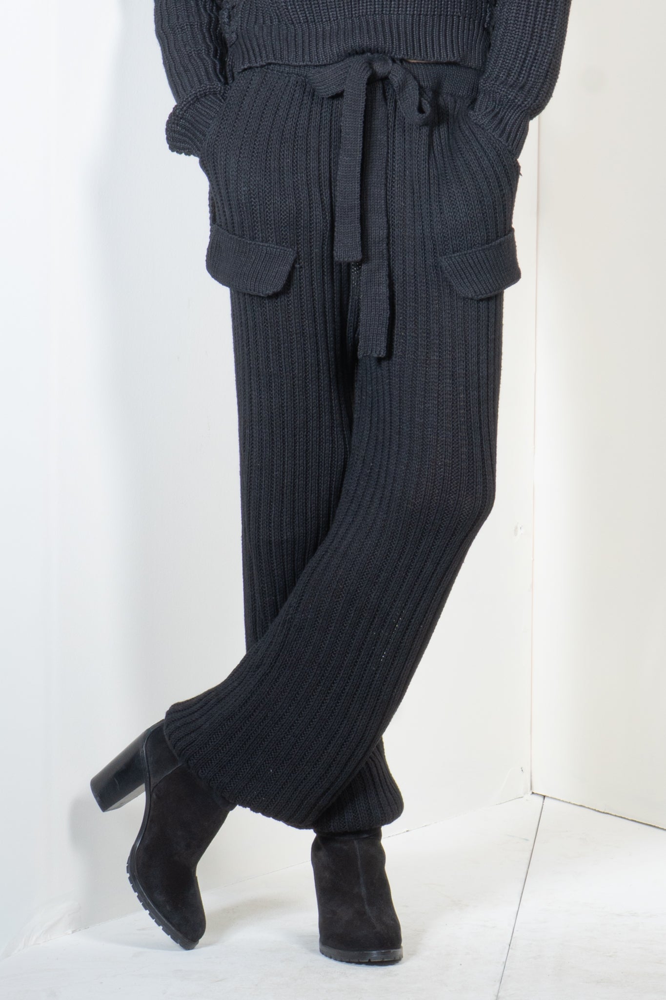 Person wearing a dark ribbed knit outfit with wide-leg pants on a white background